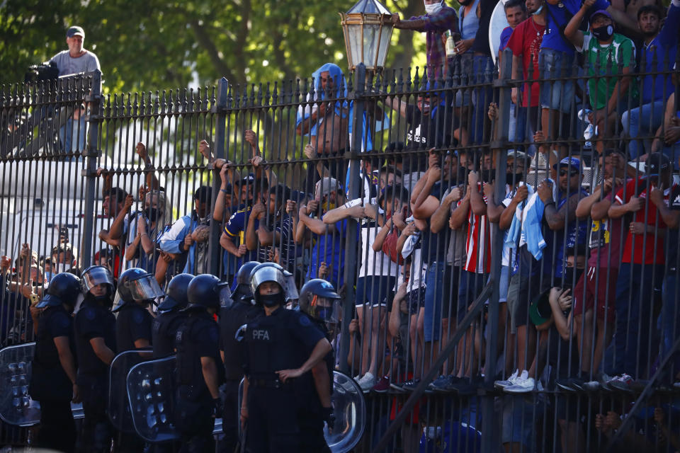 Mourning fans climb the fence of the presidential palace to get a glimpse of the casket carrying Diego Maradona's body in Buenos Aires, Argentina, Thursday, Nov. 26, 2020. The Argentine soccer great who was among the best players ever and who led his country to the 1986 World Cup title died from a heart attack at his home Wednesday at the age of 60. (AP Photo/Marcos Brindicci)