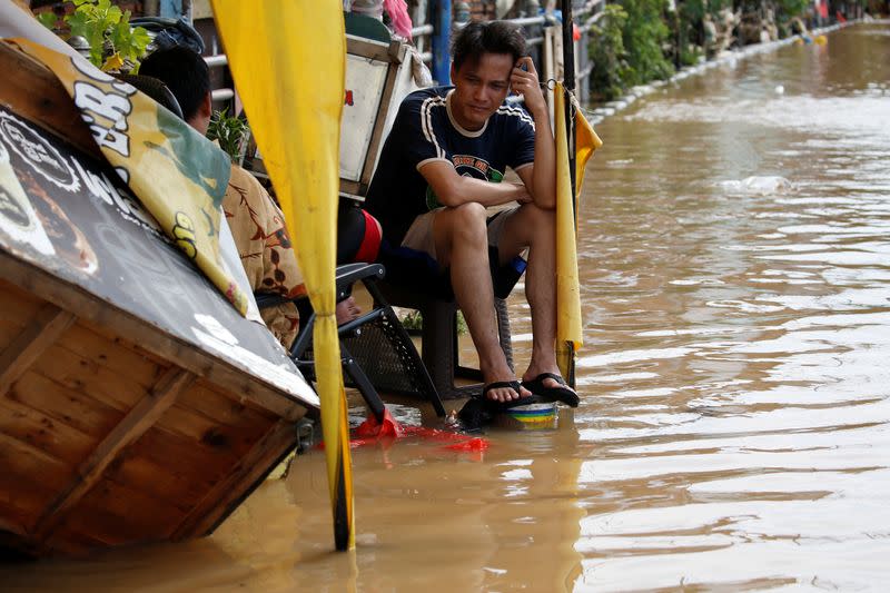 Man reacts as he sits on a chair outside his house, flooded after heavy rains in Jakarta