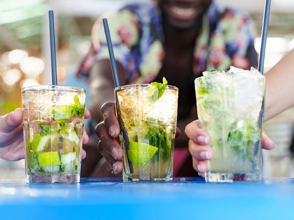 three people cheersing mojitos outside on a nice day