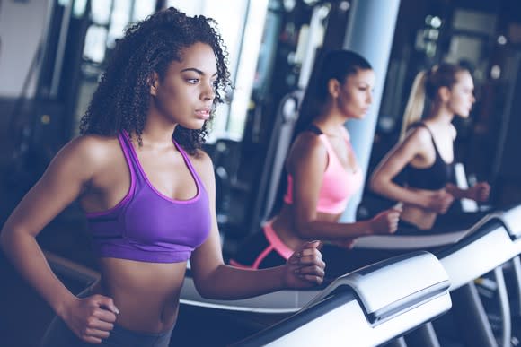 Women using running machines in a gym.