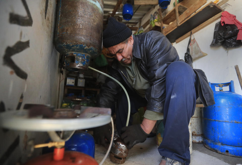 A Syrian displaced man Mohammed Zakaria, 53, who fled his Syrian hometown of Homs in 2012, fills a gas canister at his gas and oil shop which is at the entrance of his tent at a refugee camp, in Bar Elias, in eastern Lebanon's Bekaa valley, Friday, March 5, 2021. Nearly ten years later, the family still hasn't gone back and Zakaria is among millions of Syrians unlikely to return in the foreseeable future, even as they face deteriorating living conditions abroad. The Syrian conflict has resulted in the largest displacement crisis since World War II. (AP Photo/Hussein Malla)