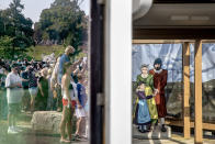 A crowd is reflected in the window of a ticket booth next to a cutout, right, of Pilgrims as they wait for the Mayflower II, a replica of the original Mayflower ship that brought the Pilgrims to America 400 year ago, to sail into Plymouth, Mass., Monday, Aug. 10, 2020. The 102 passengers aboard the Mayflower, equal numbers "saints" and "strangers," did not cross the Atlantic to establish a democratic society. When they set sail from Plymouth, England, on Sept. 16, 1620, they were escaping religious persecution and looking for a place where they could prosper. (AP Photo/David Goldman)