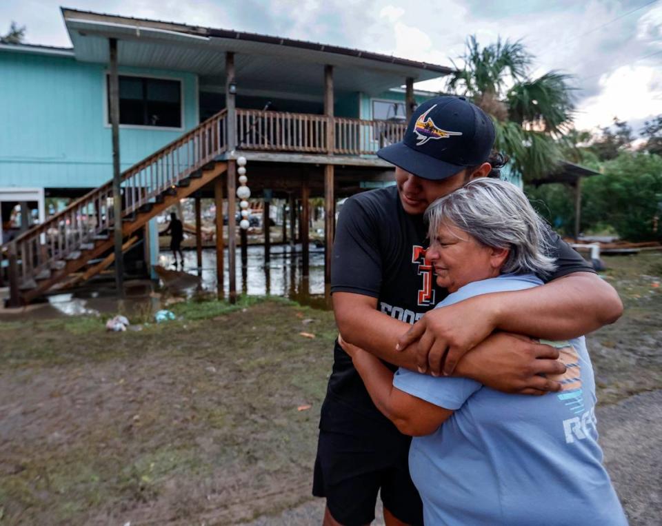 Hope Reinke hugs Rogelio Juarez outside her home in Horseshoe Beach, Florida on Wednesday, August 30, 2023. She grew emotional as she saw her stilt home still stood, even if some ground-floor rooms were destroyed.