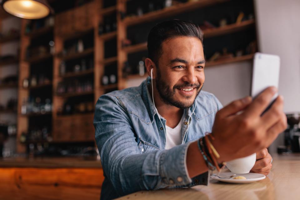 Man taking iphone video in cafe