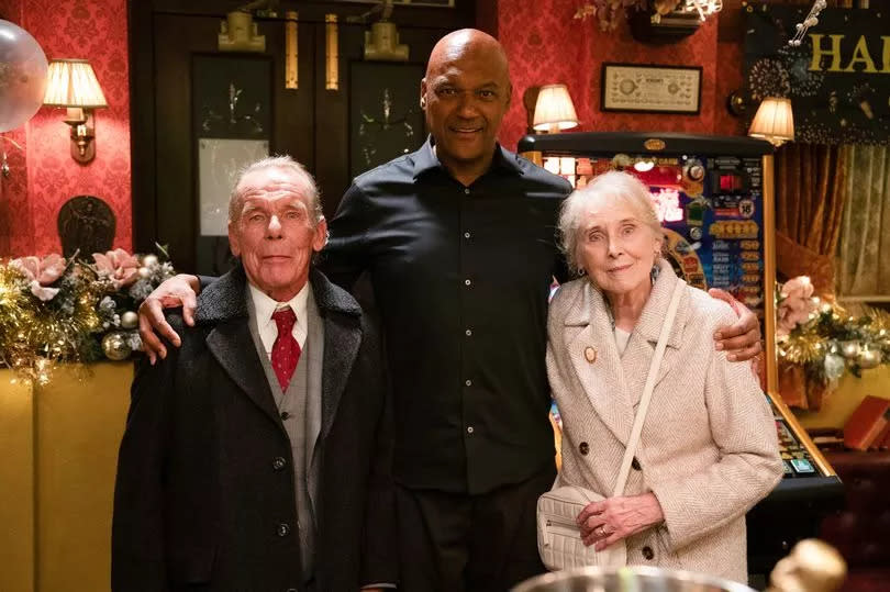 EastEnders' George Knight alongside his adoptive parents -Credit:BBC/Jack Barnes/Kieron McCarron