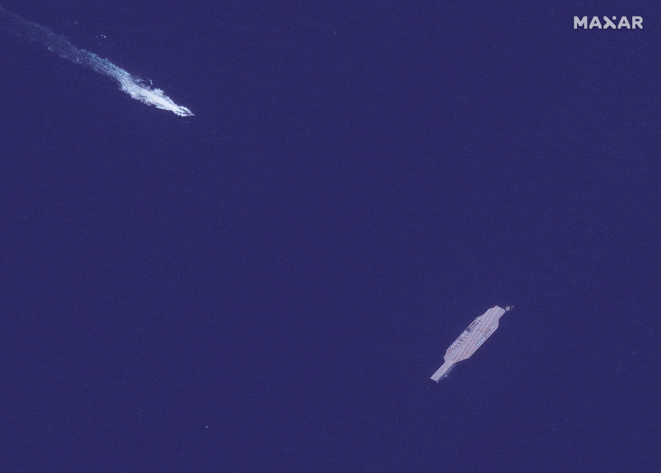 In this July 26, 2020, satellite photo provided on July 27, by Maxar Technologies, an Iranian fast boat, top left, approaches a mockup aircraft carrier built by Iran in the Strait of Hormuz. Satellite photographs released Monday, July 27, showed Iran has moved the aircraft carrier out to sea likely for naval drills amid heightened tensions between Tehran and the U.S. (Maxar Technologies via AP)