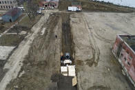 Workers wearing personal protective equipment bury bodies in a trench on Hart Island, Thursday, April 9, 2020, in the Bronx borough of New York. On Thursday, New York City’s medical examiner confirmed that the city has shortened the amount of time it will hold on to remains to 14 days from 30 days before they will be transferred for temporary internment at a City Cemetery. Earlier in the week, Mayor Bill DeBlasio said that officials have explored the possibility of temporary burials on Hart Island, a strip of land in Long Island Sound that has long served as the city’s potter’s field. (AP Photo/John Minchillo)