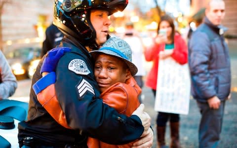 Devonte Hart hugs a police officer at a rally in Portland in an image that went viral - Credit: Johnny Huu Nguyen via AP