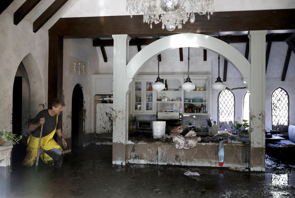 FILE - Bill Asher walks through mud in his home damaged by storms in Montecito, Calif., Thursday, Jan. 11, 2018. According to a study published in Science Advances on Friday, April 1, 2022, a one-two punch of nasty wildfires followed by heavy downpours, triggering flooding and mudslides, will strike the U.S. West far more often in a warming-hopped world, becoming a frequent occurrence. (AP Photo/Marcio Jose Sanchez, File)