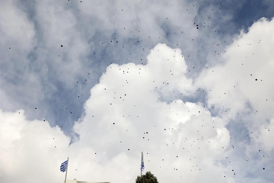 Black balloons released by protesters fly over Syntagma square, in Athens, Greece, Sunday, March 5, 2023. Thousands protesters, take part in rallies around the country for fifth day, protesting the conditions that led the deaths of dozens of people late Tuesday, in Greece's worst recorded rail accident. The banner reads "It wasn't human error." (AP Photo/Yorgos Karahalis)