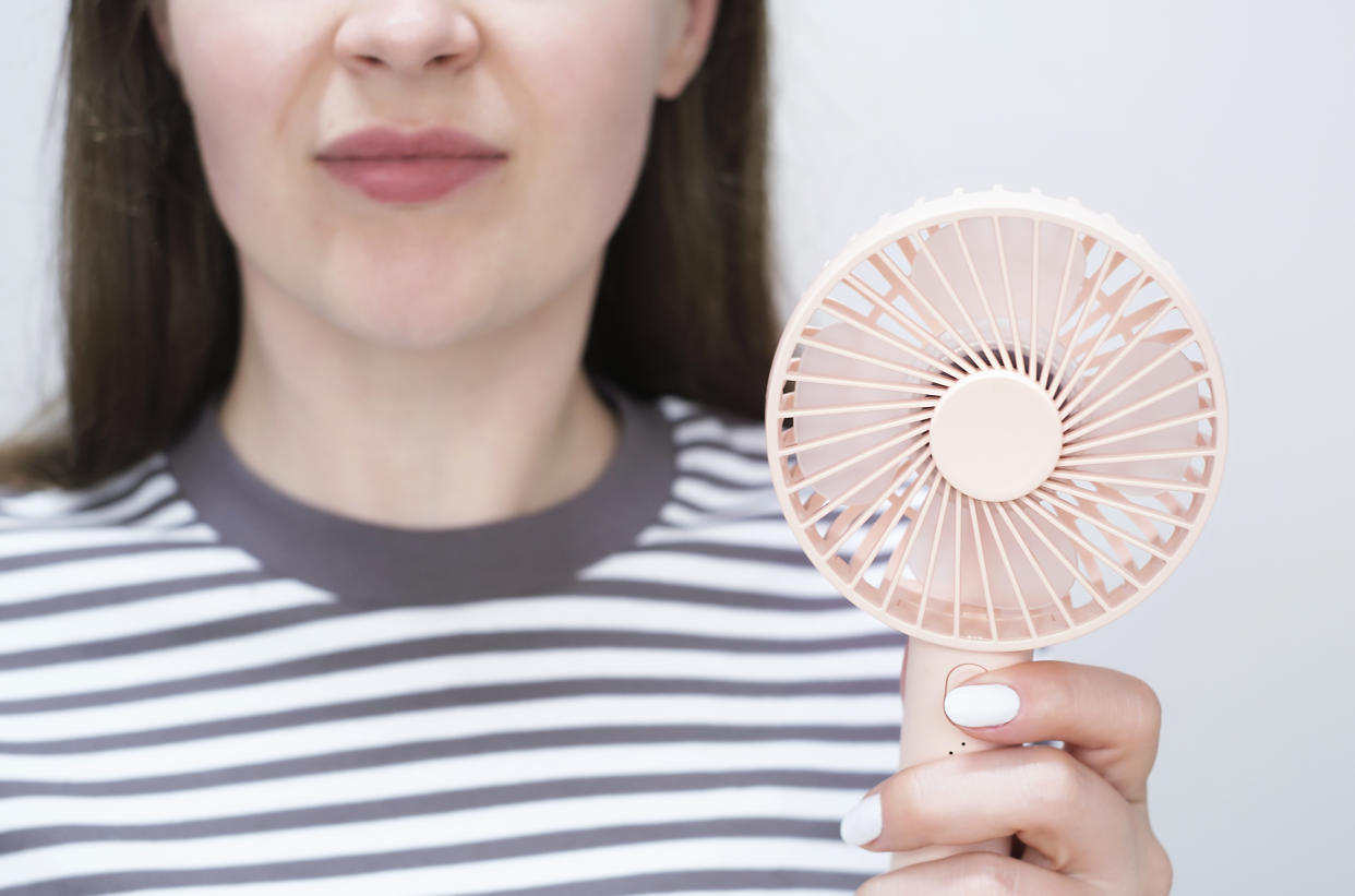 Woman holding a pink mini fan close up front view.