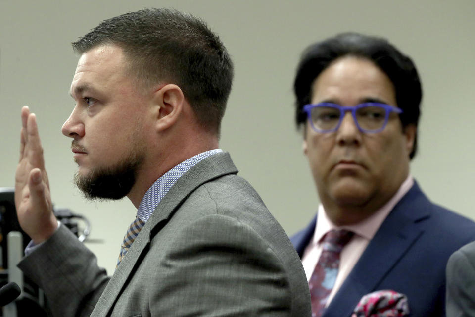 Hollywood Police detective Steven Regentz, left, is sworn in to testify during a first appearance hearing for NFL free agent Antonio Brown, Friday, Jan. 2,4 0202, at the Broward County Courthouse in Fort Lauderdale, Fla. Brown was granted bail on Friday after turning himself in at a Florida jail on charges that he and his trainer attacked the driver of a moving truck that carried some of his possessions from California. (Amy Beth Bennett/South Florida Sun Sentinel via AP, Pool)