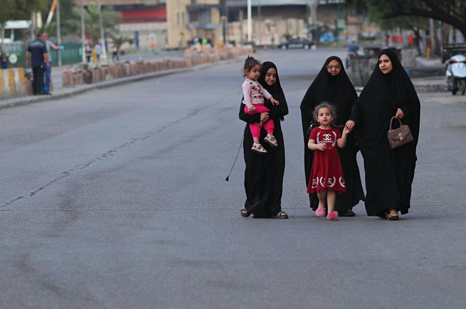 People walk in a nearly empty street during a curfew to help fight the spread of the coronavirus. in central Baghdad, Iraq, Tuesday, March 31, 2020. The virus causes mild or moderate symptoms for most people, but for some, especially older adults and people with existing health problems, it can cause more severe illness or death. (AP Photo/Hadi Mizban)