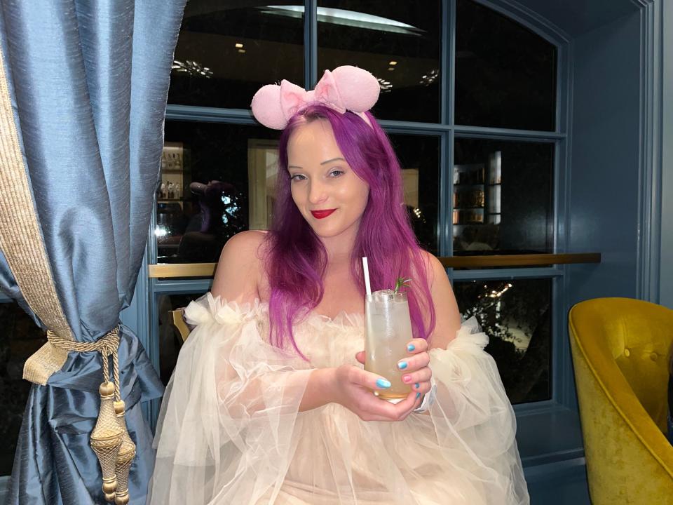 jenna posing with a rosemary cooler mocktail at the enchanted rose lounge in the grand floridian