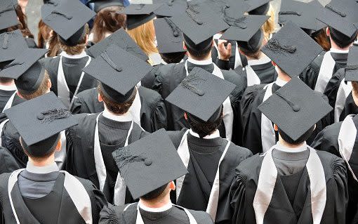 Graduate college students photographed from above wearing traditional mortar board hats and robes at their degree ceremony - oversnap