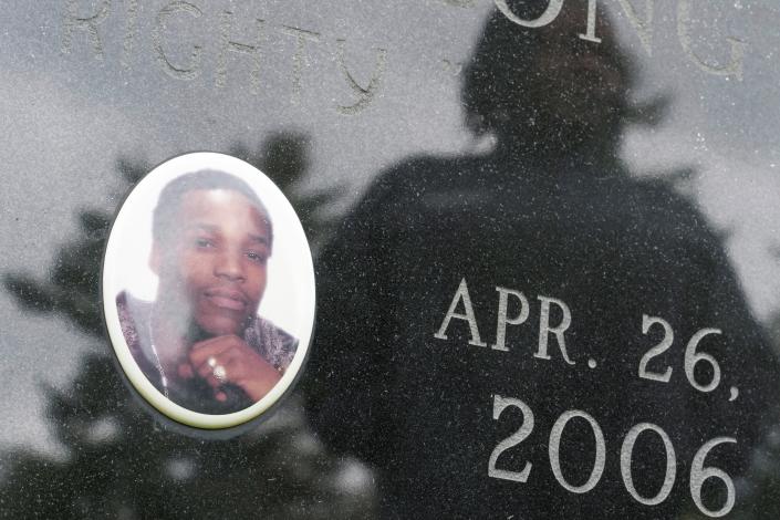 Posing for a photo at a cemetery in Poughkeepsie, N.Y., April 19, 2023, Debra Long is reflected on the gravestone of her son, Randy Long, who was murdered in 2006. An AP examination of data from 23 states shows that Black people are disproportionately denied aid from programs that reimburse victims of violent crime. (AP Photo/Seth Wenig)