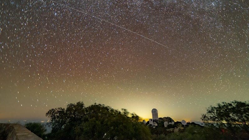 Trails in the night sky left by BlueWalker 3 are juxtaposed against the Nicholas U. Mayall 4-meter Telescope at Kitt Peak National Observatory, a Program of NSF's NOIRLab. The lights from Tucson, Arizona, are seen in the background.