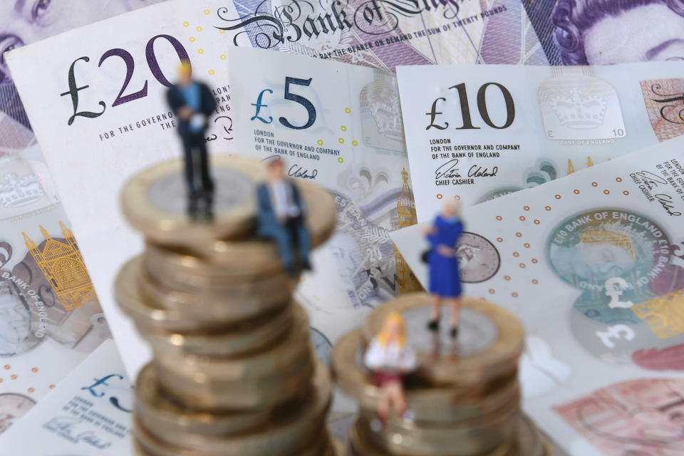 Models of men and women on a pile of coins and bank notes.