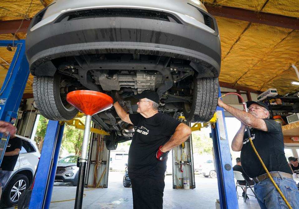 Volunteers Stan Dinwoodie, left, and Jonnie Walker change the oil in a vehicle at Suncoast Community Church of Sarasota. The church also partners with Mothers Helping Mothers to provide donated cars to families in need.