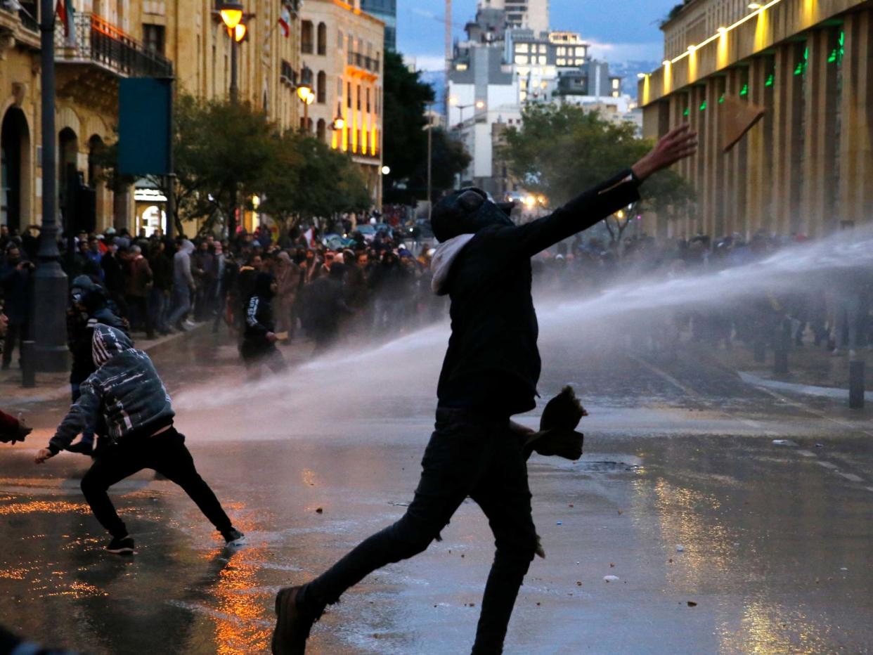 Anti-government protesters throw stones at the riot police during ongoing protests in Beirut last month: AP