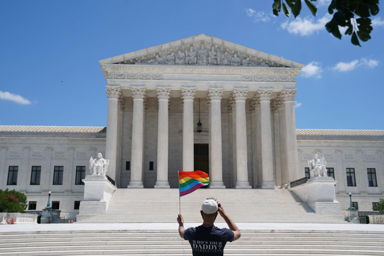 A person waves a rainbow flag in front of the Supreme Court on June 15, 2020, when the court ruled in Bostock v. Clayton County that a landmark civil rights law protects gay and transgender workers from workplace discrimination.