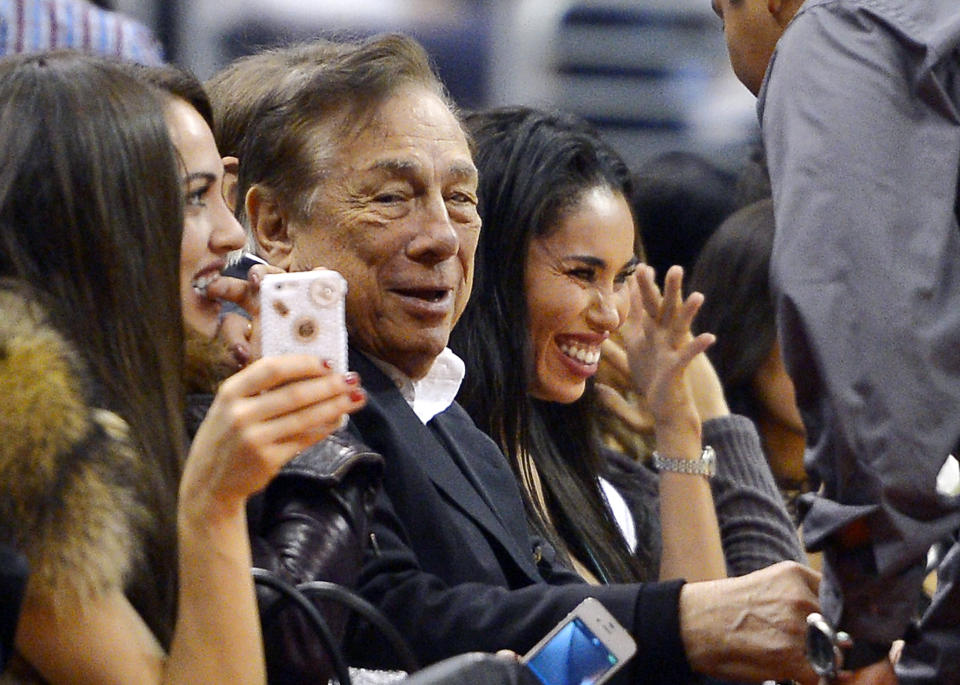 In this photo taken on Friday, Oct. 25, 2013, Los Angeles Clippers owner Donald Sterling, center, and V. Stiviano, right, watch the Clippers play the Sacramento Kings during the first half of an NBA basketball game, in Los Angeles. The NBA is investigating a report of an audio recording in which a man purported to be Sterling makes racist remarks while speaking to his Stiviano. NBA spokesman Mike Bass said in a statement Saturday, April 26, 2014, that the league is in the process of authenticating the validity of the recording posted on TMZ's website. Bass called the comments "disturbing and offensive." (AP Photo/Mark J. Terrill)