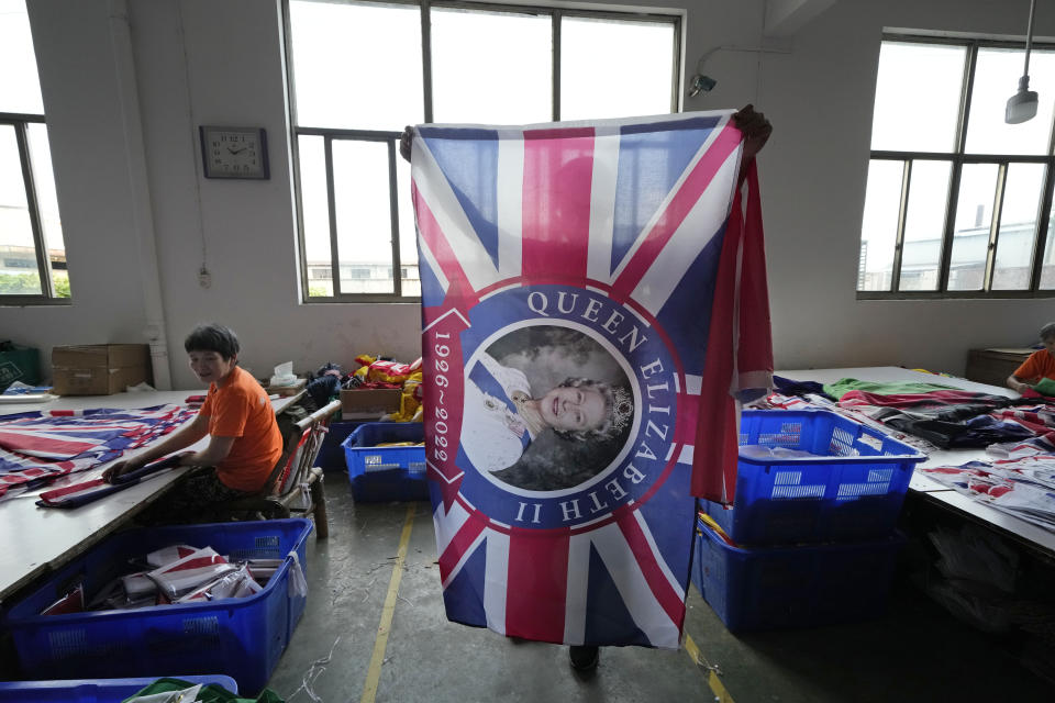 A worker holds up a flag with the Queen's image at the Shaoxing Chuangdong Tour Articles Co. factory in Shaoxing, in eastern China's Zhejiang province, Friday, Sept. 16, 2022. Ninety minutes after Queen Elizabeth II died, orders for thousands of British flags started to flood into the factory south of Shanghai. (AP Photo/Ng Han Guan)