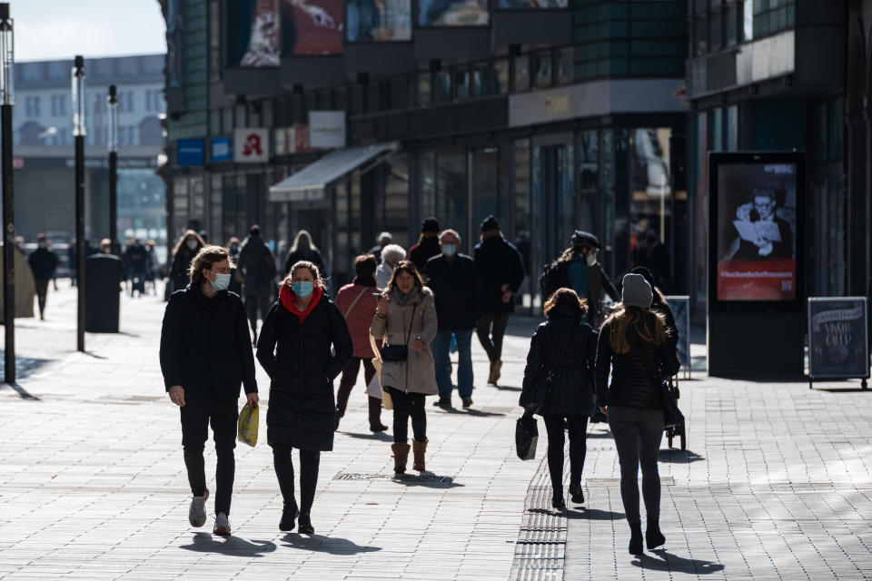 Passers-by walk in a shopping street as lockdown measures ease during the novel coronavirus pandemic on March 8, 2021 in Leipzig, Germany. Shops are opening nationwide today under strict conditions according to the infection rates in their respective regions. In areas with incidence rates between 50 and 100, which accounts for much of Germany, customers must book an appointment online to enter the store. Infection rates, which had been falling continuously since December, have levelled off and even begun to climb in recent weeks, which authorities attribute to the spread of the B117 coronavirus variant. (Photo by Jens Schlueter/Getty Images)