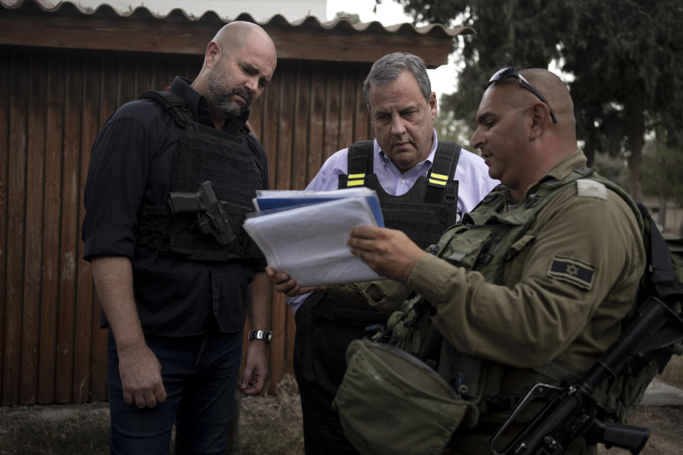 Former New Jersey Governor Chris Christie, center, looks at crime scene photos as he visits Kibbutz Kfar Azza, near the Israel-Gaza border, the site of an Oct. 7 massacre by Hamas, with Israel's Knesset Speaker Amir Ohana, left and Israeli Army Maj. Diamond, right, Sunday, Nov. 12, 2023. (AP Photo/Maya Alleruzzo)