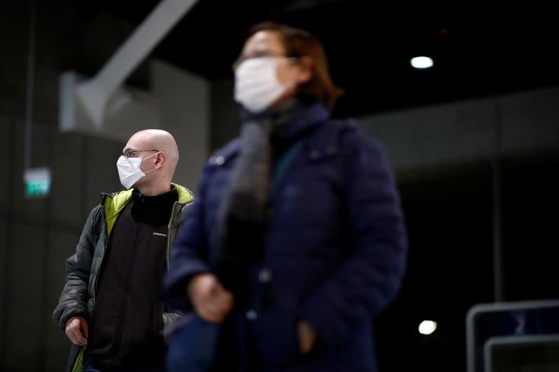 Travellers wearing masks arrive on a direct flight from China, in Paris