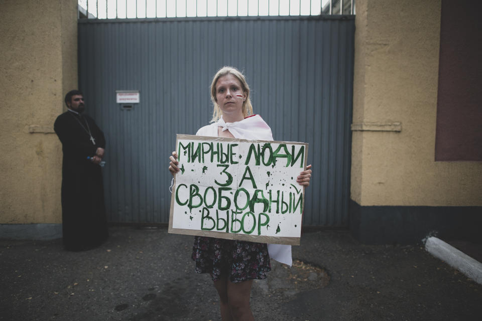 Valeria, 19, a student poses for a photo holding a handmade poster that reads "Peaceful people for the free choice" during an opposition rally in front of a detention center in Minsk, Belarus, Monday, Aug. 17, 2020. (AP Photo/Evgeniy Maloletka)