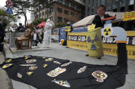 An environmental activist wearing a mask of Japanese Prime Minister Yoshihide Suga performs to denounce the Japanese government's decision on Fukushima water, near the Japanese embassy in Seoul, South Korea, Tuesday, April 13, 2021. Japan's government decided Tuesday to start releasing massive amounts of treated radioactive water from the wrecked Fukushima nuclear plant into the Pacific Ocean in two years - an option fiercely opposed by local fishermen and residents. (AP Photo/Lee Jin-man)