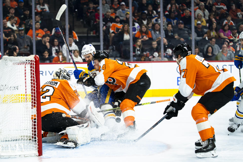 Philadelphia Flyers' Felix Sandstrom, left, makes the save on a shot by Buffalo Sabres' Zemgus Girgensons, center left, as Philadelphia Flyers' Nick Seeler, center right, pushes Girgensons away during the first period of an NHL hockey game Saturday, April 1, 2023, in Philadelphia. (AP Photo/Chris Szagola)