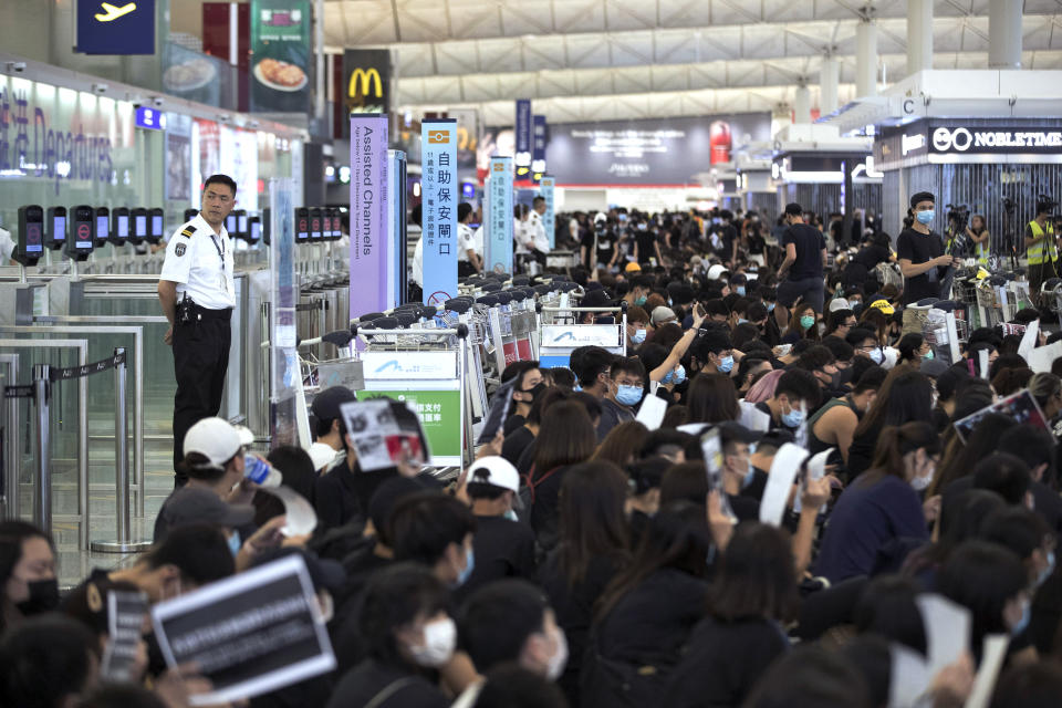 Airport security personnel look on as protesters using luggage trolleys to block the departure gates during a demonstration at the Airport in Hong Kong, Tuesday, Aug. 13, 2019. (Photo: Vincent Yu/AP)