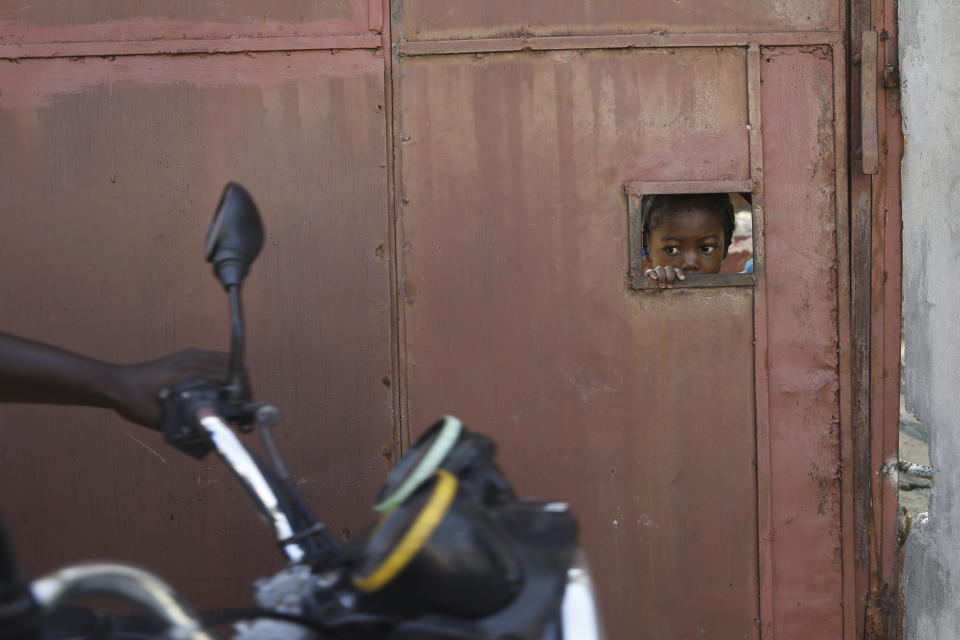 FILE - A child watches from an opening in a security gate as residents flee their homes due to gang violence, in Port-au-Prince, Haiti, March 9, 2024. Thousands of people have been killed and displaced by gangs fighting for control of Port-au-Prince. (AP Photo/Odelyn Joseph, File)