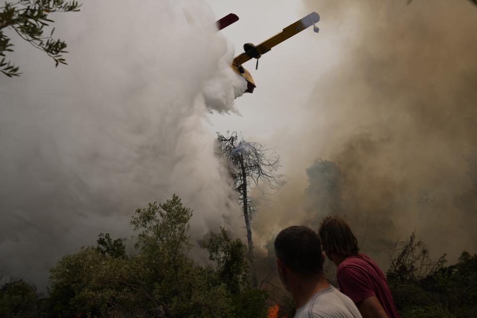 An aircraft drops water over a wildfire at Ellinika village on Evia island, about 176 kilometers (110 miles) north of Athens, Greece, Monday, Aug. 9, 2021. Firefighters and residents battled a massive forest fire on Greece's second largest island for a seventh day Monday, fighting to save what they can from flames that have decimated vast tracts of pristine forest, destroyed homes and businesses and sent thousands fleeing. (AP Photo/Petros Karadjias)