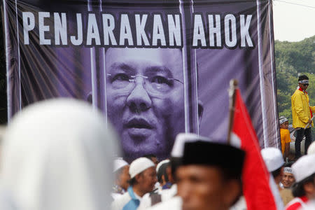 Members of hardline Muslim groups stand around a poster during protest against Jakarta's incumbent governor Basuki Tjahaja Purnama. The poster reads "Ahok should be jailed". REUTERS/Iqro Rinaldi