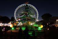 People walk past a giant Christmas tree near a Ferris wheel on the place Massena as part of Christmas holiday season illuminations in Nice December 11, 2013. REUTERS/Eric Gaillard (FRANCE - Tags: SOCIETY TRAVEL)