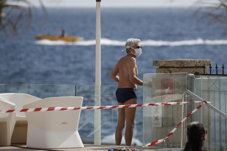 A tourist in quarantine inside the H10 Costa Adeje Palace hotel in La Caleta, in the Canary island of Tenerife, Spain, Thursday, Feb. 27, 2020. Spanish officials say a tourist hotel on the Canary Island of Tenerife has been placed in quarantine after an Italian doctor staying there tested positive for the COVID-19 virus. (AP Photo/Joan Mateu)