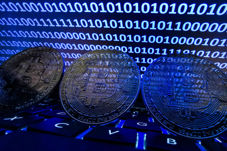 Representation of Bitcoin seen with binary code displayed on a laptop screen.