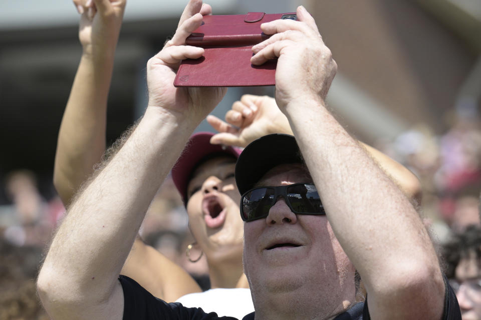 A spectator views a solar eclipse with his cell phone during the first half of an NCAA college football game between Florida State and Syracuse, Saturday, Oct. 14, 2023, in Tallahassee, Fla. (AP Photo/Phelan M. Ebenhack)