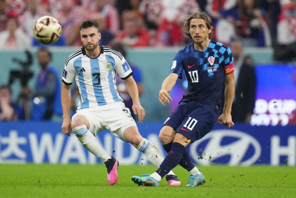 Croatia's Luka Modric, right, kicks the ball as Argentina's Nicolas Tagliafico watches during the World Cup semifinal soccer match between Argentina and Croatia at the Lusail Stadium in Lusail, Qatar, Tuesday, Dec. 13, 2022. (AP Photo/Petr David Josek)