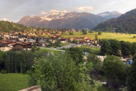 The sun sets during a train journey to Davos, Switzerland, Saturday, May 21, 2022. The World Economic Forum is encouraging European attendees to come to its exclusive gathering in the Swiss Alps by train. Its part of efforts to burnish the sustainability credentials for an event in Davos that conjures up up images of government leaders, billionaire elites and corporate titans jetting in on carbon-spewing private planes.(AP Photo/Kelvin Chan)