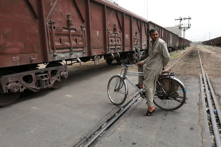 A man on a bicycle waits to cross a passageway as cargo train passes in Karachi, Pakistan September 16, 2018. REUTERS/Akhtar Soomro