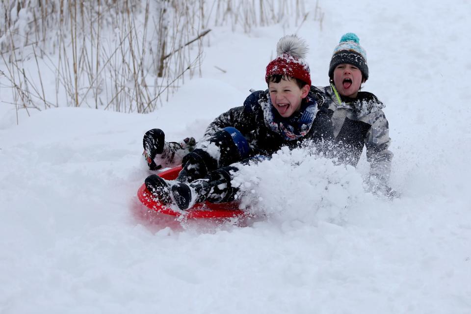 From left, Portsmouth residents Jonah Lewis, 9, and Colton McCain, 10, sled down a hill on Feb. 2, 2021 in Portsmouth during a snow storm.