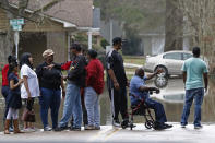 Area residents observe the swirling Pearl River floodwaters drain from North Canton Club Circle in Jackson, Miss., Tuesday, Feb. 18, 2020. Officials have limited entry to the flooded neighborhoods as they have warned residents about the contamination of the receding waters and the swift currents. (AP Photo/Rogelio V. Solis)