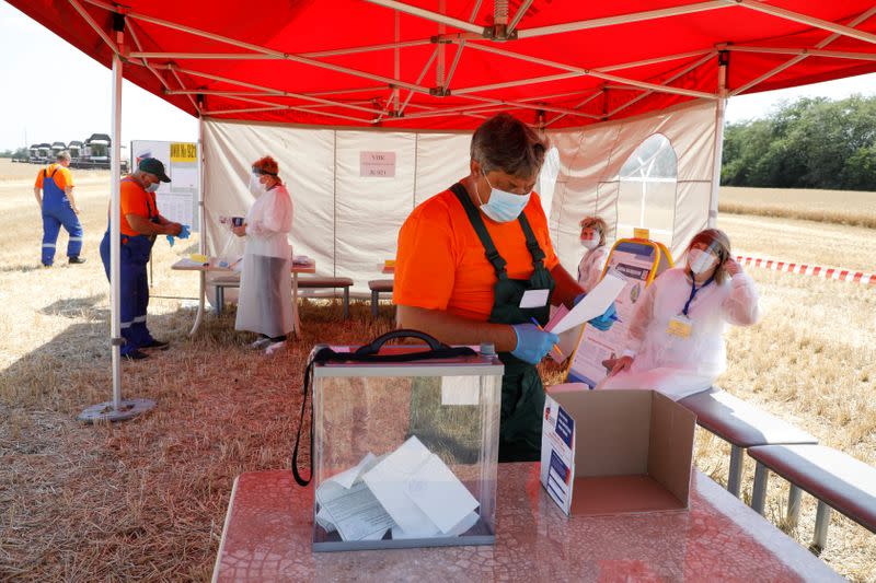 Combine drivers visit a mobile polling station during a nationwide vote on constitutional reforms in Stavropol Region