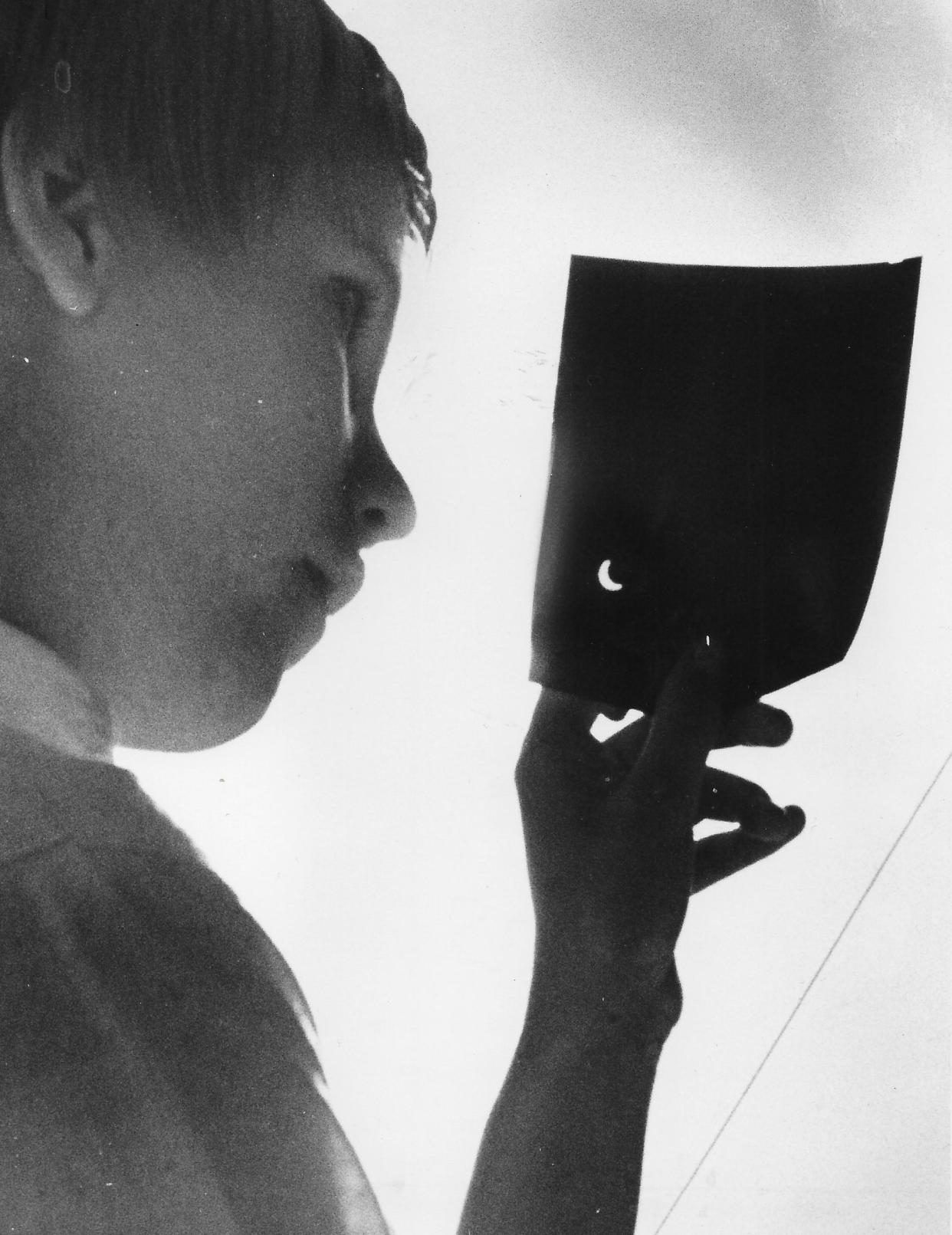 Bobbi Wirth, 15, of Stow, uses a sheet of exposed, developed film to view a partial eclipse July 20, 1963.
