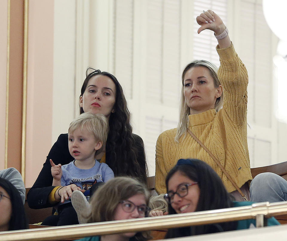 FILE - In this May 22, 2019, file photo, an opponent of a measure to toughen the rules for vaccination exemptions gives a thumbs down as the bill's author, state Sen. Richard Pan, D-Sacramento, makes his closing statements in Sacramento, Calif. California Gov. Gavin Newsom and Pan have agreed to limit the role of public health officials in approving doctors' vaccine decisions. But the health officials will increase their oversight of doctors and schools with high numbers of medical exemptions. Sen. Richard Pan announced the changes Tuesday, June 18 after Newsom said he had doubts about giving state public health officials instead of local doctors the authority to decide which children can skip their shots before attending school. (AP Photo/Rich Pedroncelli, File)