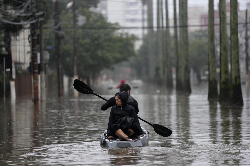 Residents row a boat in a flooded street after heavy rains, in Porto Alegre, Rio Grande do Sul state, Brazil, Saturday, May 11, 2024. (AP Photo/Andre Penner)